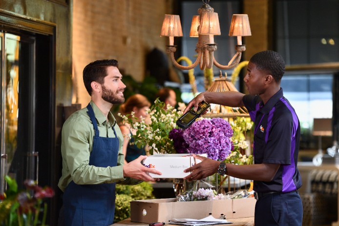 FedEx Courier scanning package while talking to boutique employee